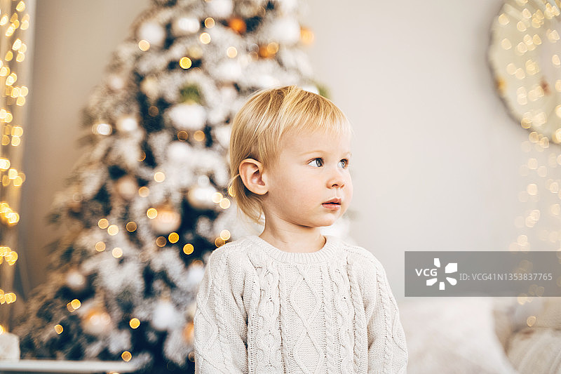 身穿粉色圣诞毛衣的可爱宝宝等待节日礼物图片素材