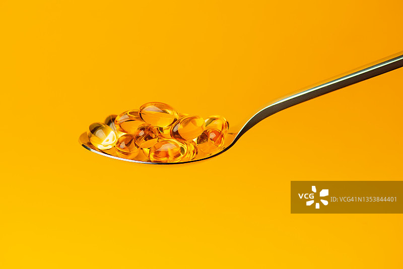 维生素D胶囊与欧米茄3勺子图片素材