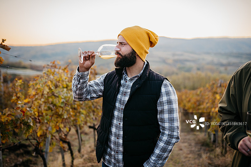 一位女士在葡萄园里看着一瓶葡萄酒图片素材