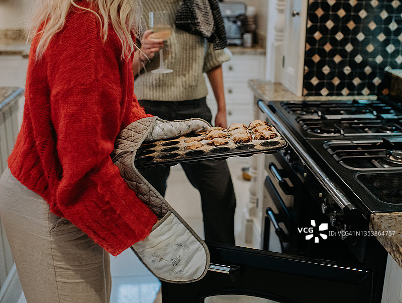 一个女人从烤箱里取出新鲜出炉的自制肉馅饼图片素材