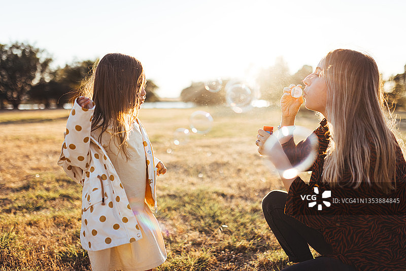 年轻母亲和女儿在公园里玩肥皂泡图片素材