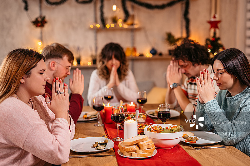 朋友们在节日晚餐前祈祷图片素材