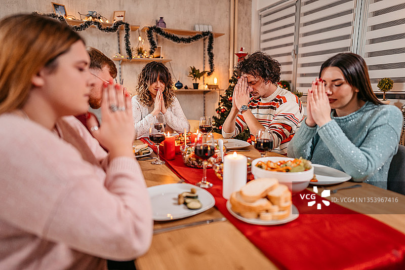 朋友们在节日晚餐前祈祷图片素材