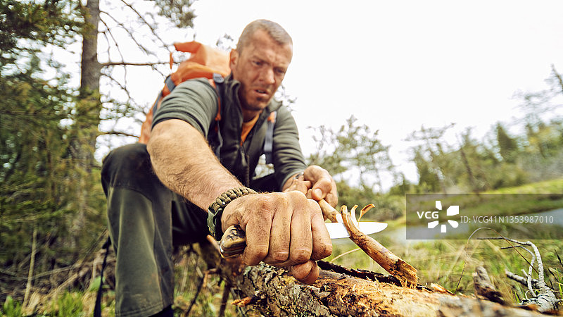 男人用刀削尖树枝图片素材