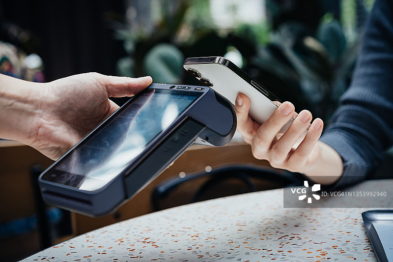 餐厅内，女人用智能手机进行移动支付，扫描并支付账单特写图片素材