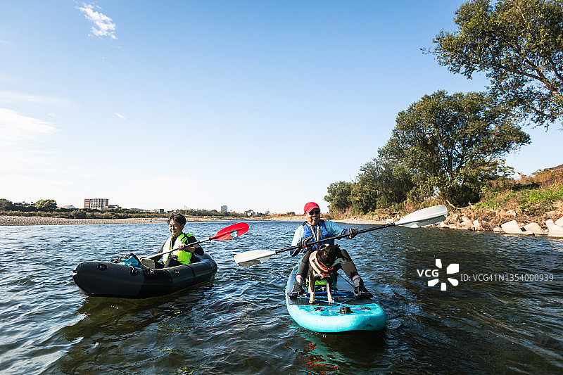 一群成年人在城市河流上享受划独木舟和桨板运动图片素材