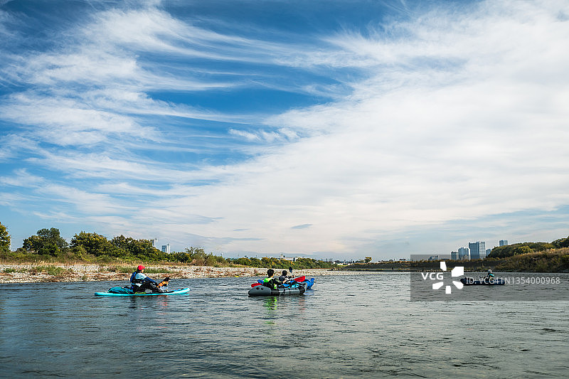 一群成年人在城市河流上享受划独木舟和桨板运动图片素材