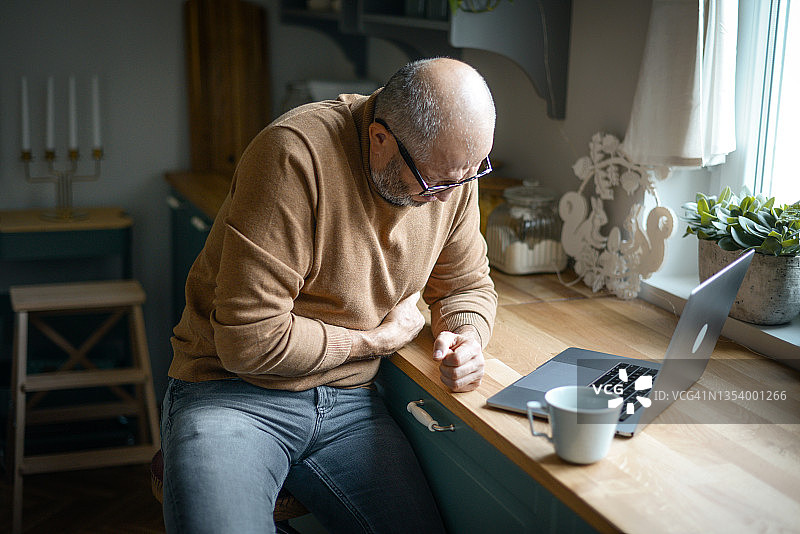 中年男人在舒适的家庭厨房内（笔记本电脑，负面情绪）图片素材