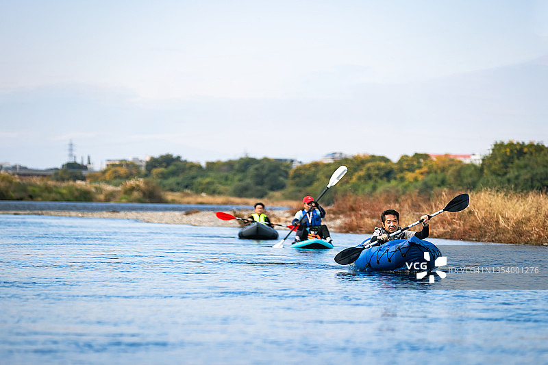 一群成年人在城市河流上享受划独木舟和桨板运动图片素材