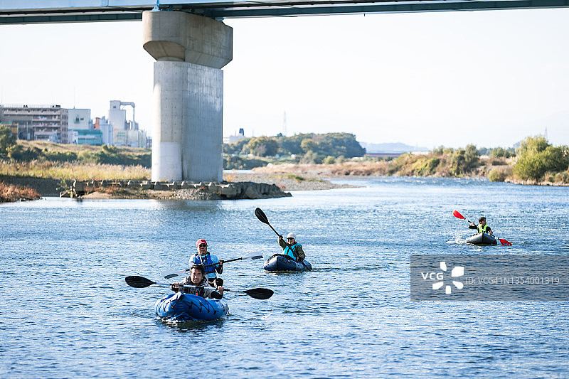 一群成年人在城市河流上享受划独木舟和桨板运动图片素材