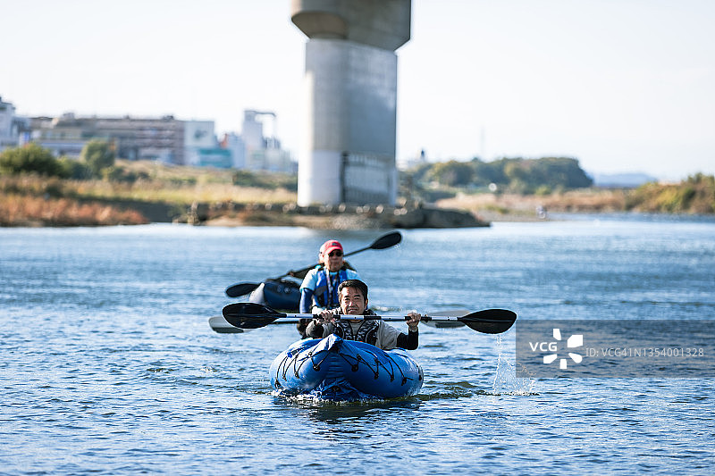 一群成年人在城市河流上享受划独木舟和桨板运动图片素材