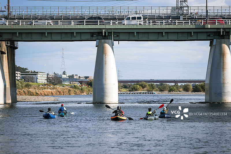 一群成年人在城市河流上享受划独木舟和桨板运动图片素材