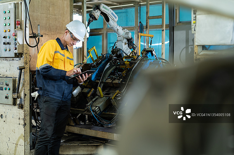 白人工程师检查工业系统的压力设备，并检查机器人在工厂执行其操作的工作过程图片素材