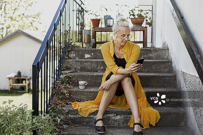 女人坐在台阶上，使用手机图片素材