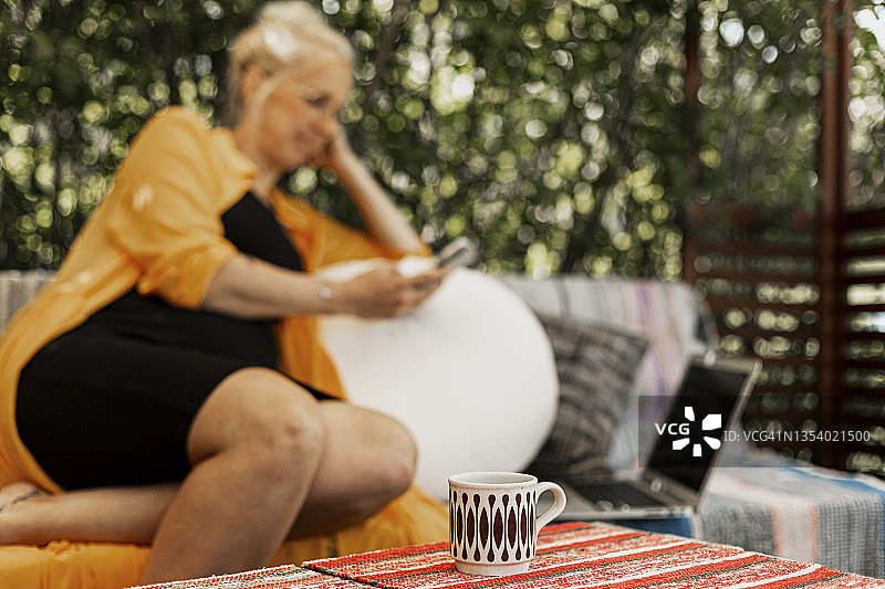 花园桌上的杯子，背景中的女人图片素材
