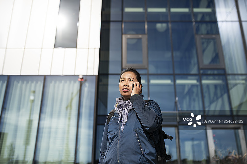 在办公楼前使用手机的年轻女人图片素材