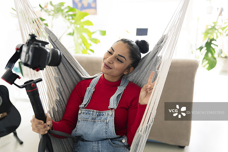 微笑且有魅力的年轻女人对着镜头微笑和挥手，并录制自己图片素材
