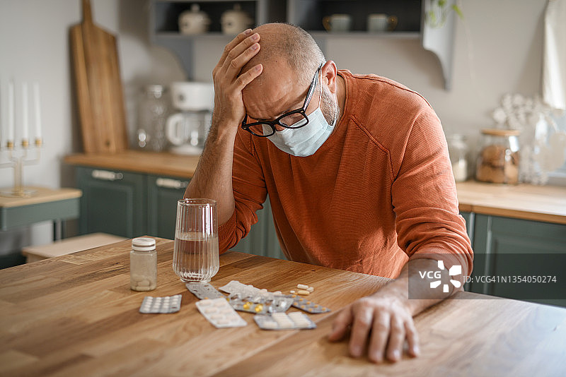 在舒适的家庭厨房里的中年男人（正在服药）图片素材