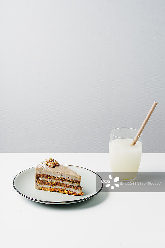 盘子里的一块素食蛋糕和一杯马铃薯或燕麦奶，白色背景图片素材