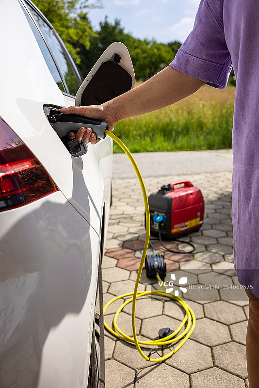 女子在家给电动汽车充电图片素材
