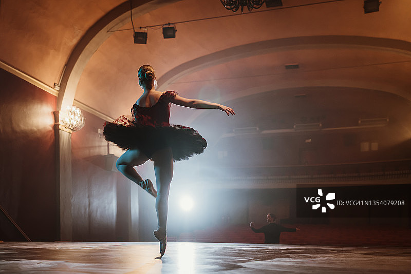 年轻芭蕾舞女演员在舞台上排练的背影图片素材