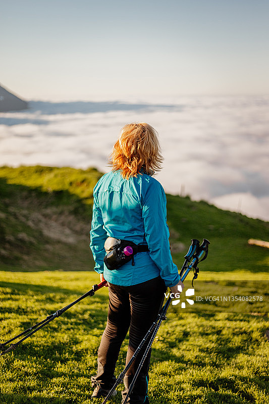 手持登山杖站在山上的中年女徒步旅行者图片素材