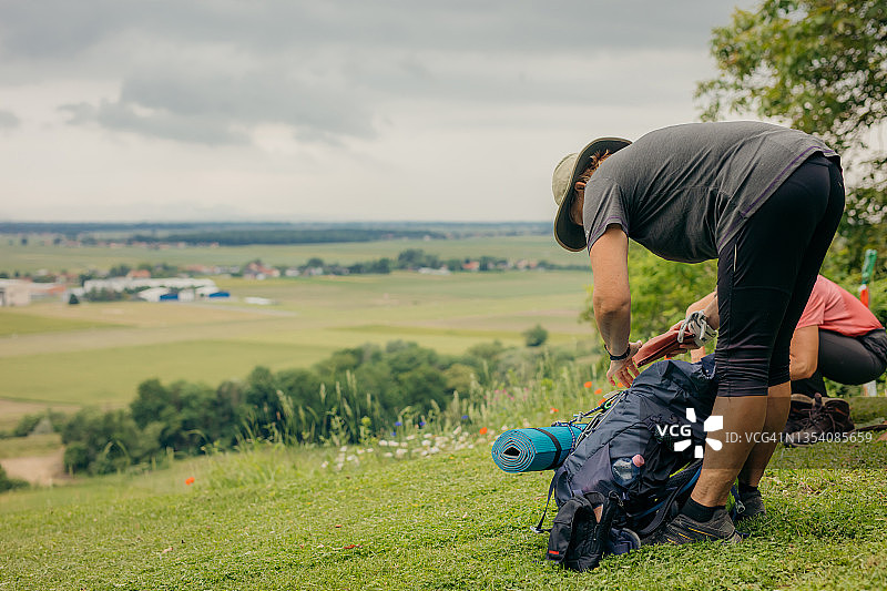 中年女徒步旅行者在山坡上整理背包图片素材
