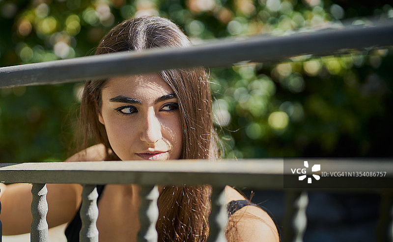 前景是钢栅栏的棕发女人特写镜头图片素材