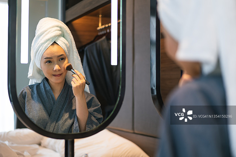 亚洲女性在镜子前用刷子涂腮红图片素材