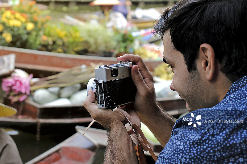 年轻男人用老式胶片相机拍照，旅行摄影概念图片素材