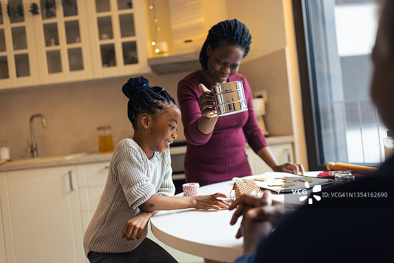 小女孩和妈妈、爷爷一起制作圣诞姜饼屋图片素材