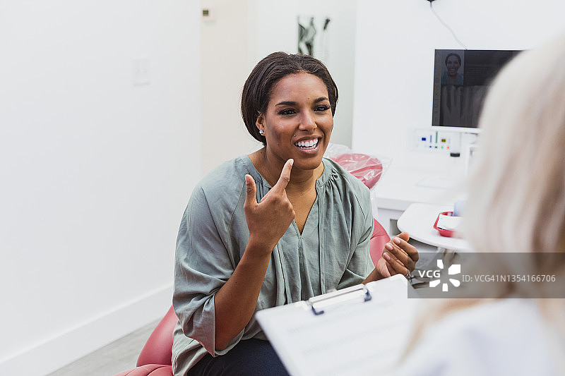 女人指着嘴里的疼痛之处，无法辨认的牙医正在倾听图片素材