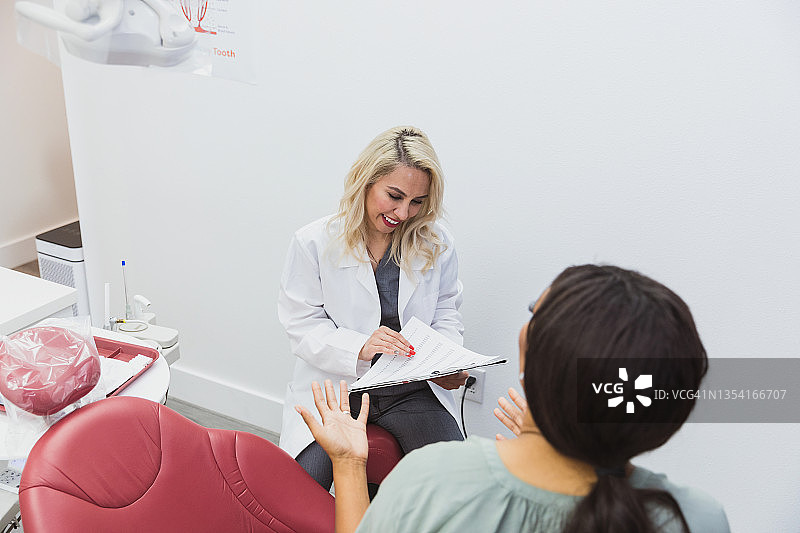 患者讲述牙科病史时，牙医查看记录图片素材