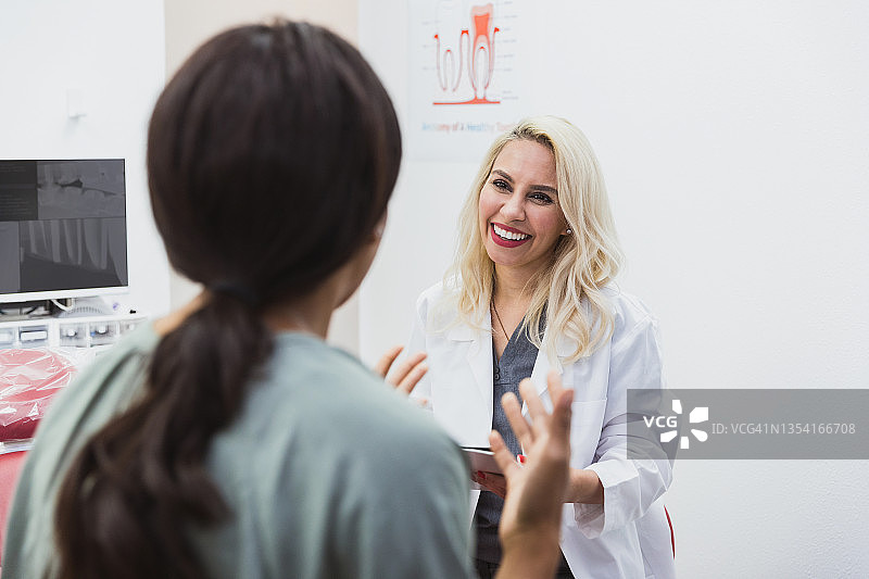 女牙医微笑倾听患者描述牙痛图片素材