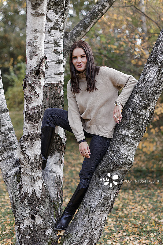 在桦树上的微笑年轻女子图片素材