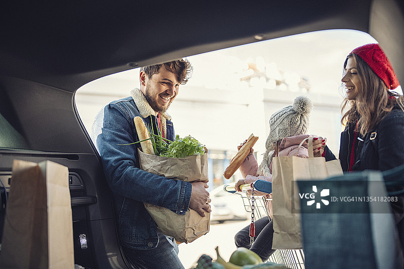 快乐家庭将购物袋装入汽车后备箱图片素材