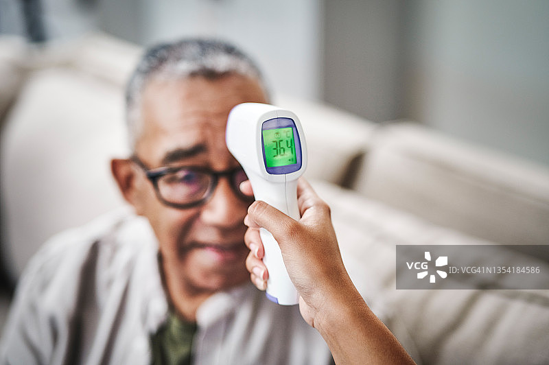 年长的男人坐在沙发上测体温图片素材