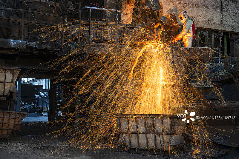 工人倾倒熔融金属时产生火花图片素材