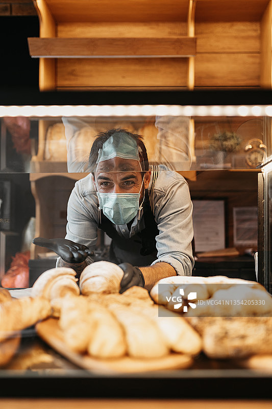 在面包店工作的戴防护口罩的英俊男人图片素材
