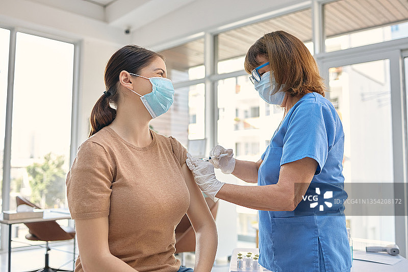 年长的医生在诊所给病人接种疫苗图片素材