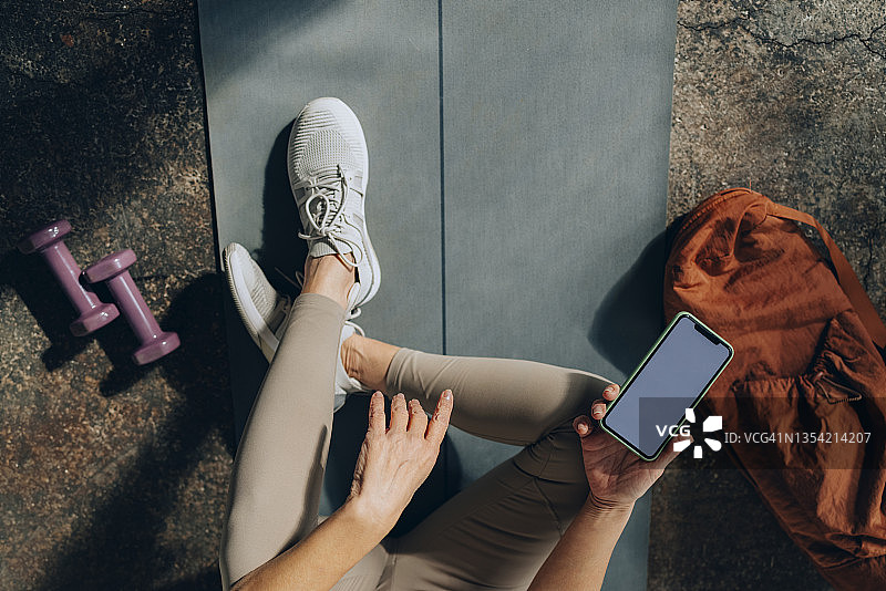 家庭锻炼前使用手机的女人双手顶视图图片素材