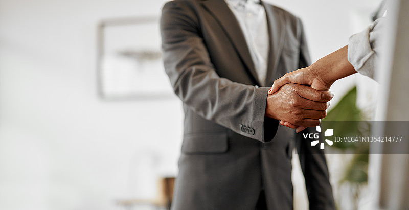 办公室里两个身份不明的商人握手的特写镜头图片素材