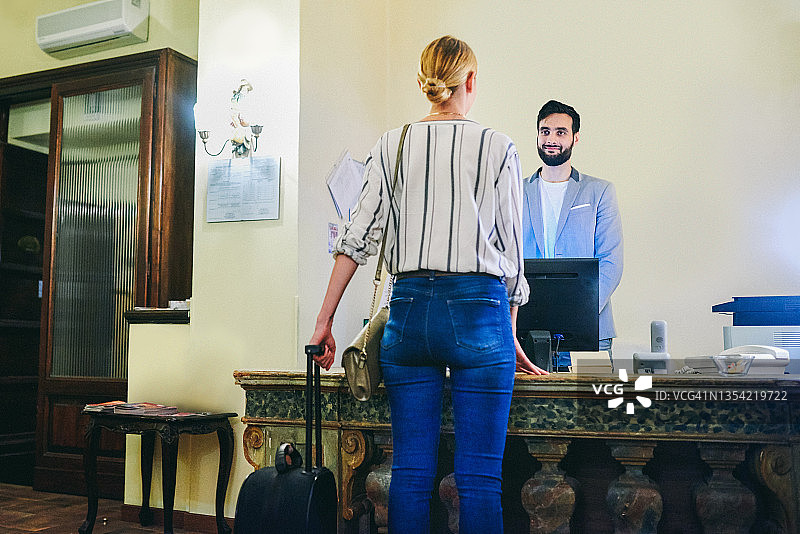 酒店前台接待女访客的年轻男接待员图片素材
