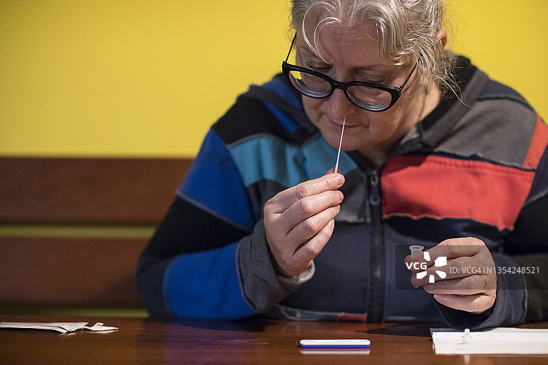 中年妇女用鼻拭子进行新冠病毒自测图片素材