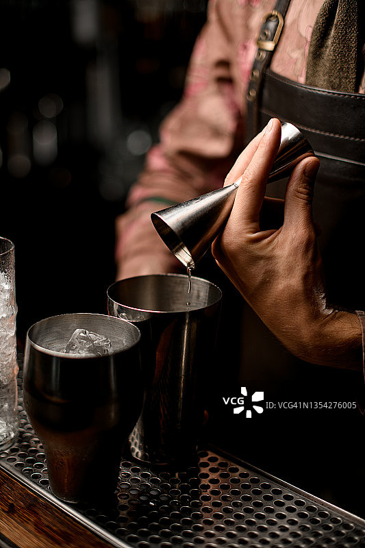 男调酒师用量酒器将饮品倒入调酒器图片素材