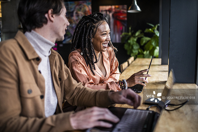 在咖啡店里交谈欢笑的年轻男女图片素材