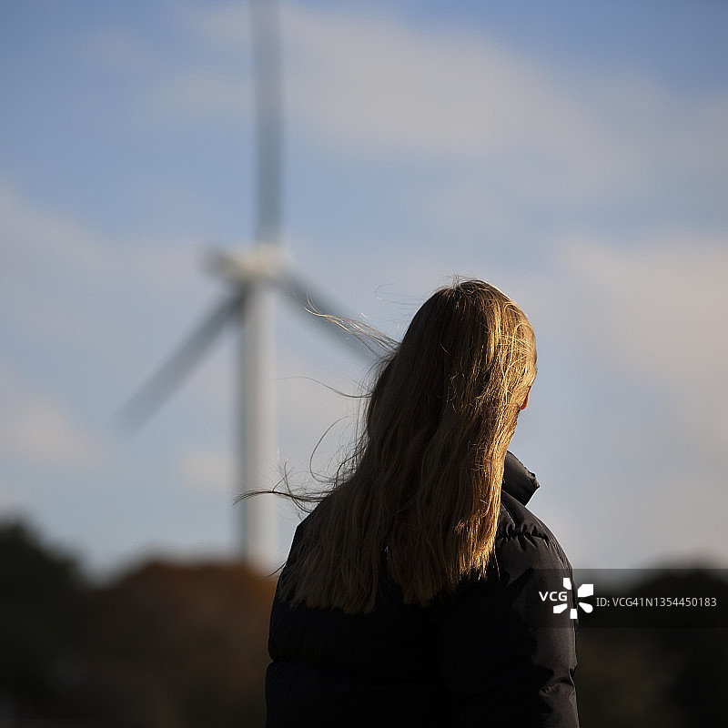 女孩看着风力涡轮机图片素材