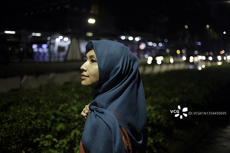 年轻的亚洲戴头巾女子在等公共汽车，城市之旅图片素材