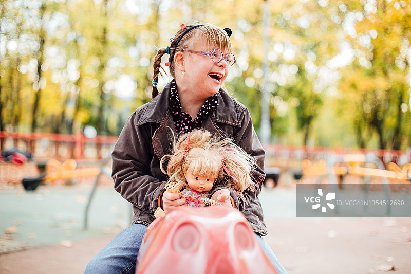 患有唐氏综合征的可爱女孩在操场上玩耍图片素材
