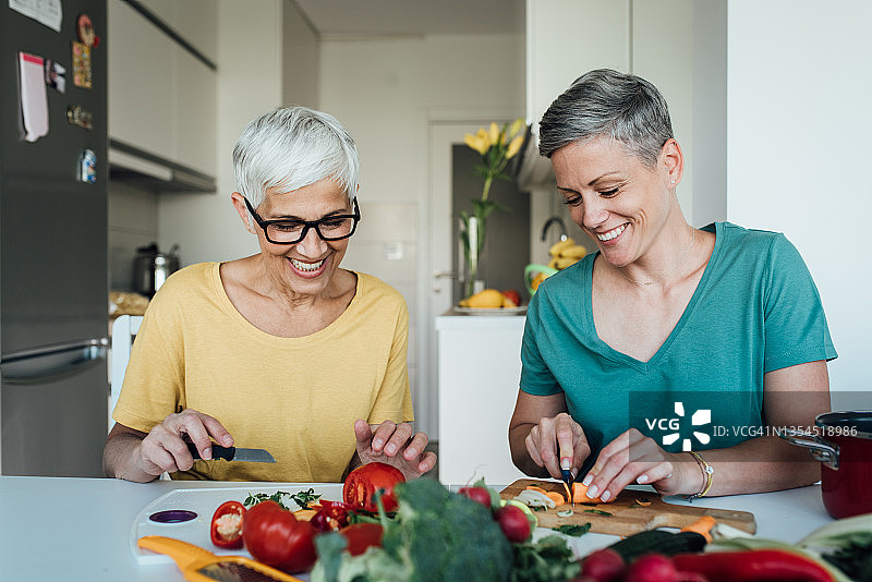 快乐的妈妈和女儿准备新鲜蔬菜肖像图片素材